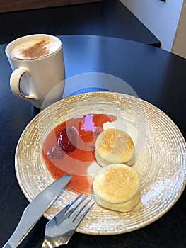 Latte with cinnamon and cheesecakes with strawberry jam