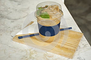 Latte coffee frappe in plastic cup serve on wooden plate at cafe coffee shop photo