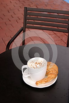 Latte with croisant outside on red brick photo