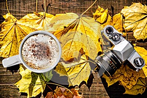 Latte and Film Camera Sitting on Leaf Covered Table photo