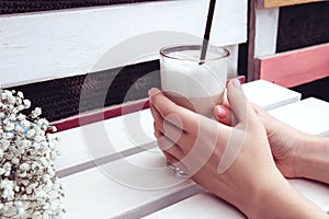 Latte in a glass with a straw on a white wooden bench