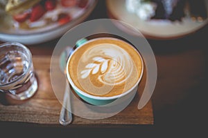 Latte hot coffee with foam milk art on a wooden table