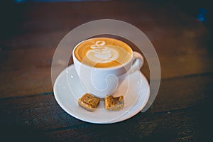 Latte hot coffee with foam milk art on a wooden table