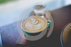 Latte hot coffee with foam milk art on a wooden table