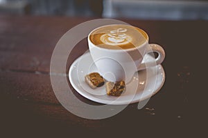 Latte hot coffee with foam milk art on a wooden table