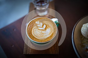 Latte hot coffee with foam milk art on a wooden table