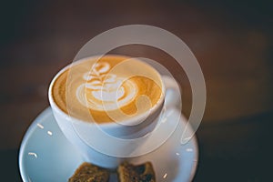 Latte hot coffee with foam milk art on a wooden table