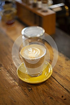 Latte. Hot latte coffee is served in clear latte glasses with ceramic class placemats on a wooden table