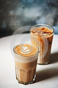 Latte and ice latte in coffee glasses on table in cafe.