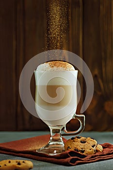 latte macchiato in glass cup with falling cinnamon powder