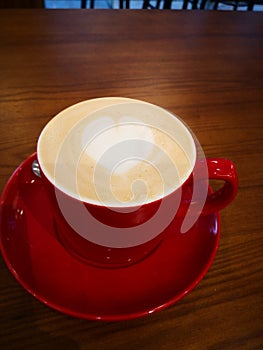 Latte in red cup with heart shape decorated