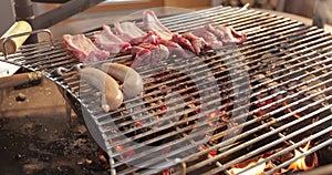 On a lattice a grill pickled meat, ribs spread, sausages, a stake, naked flame, red coals, a smoke, firewood, hands of