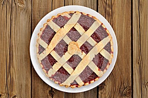 Lattice round cake with strawberry jam on wooden background