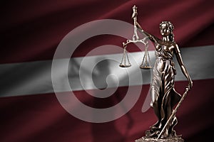 Latvia flag with statue of lady justice and judicial scales in dark room. Concept of judgement and punishment