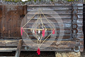 Latvian Puzurs with red ribbons hanging at log hut. Puzurs is traditional Latvian room decoration made of straws.