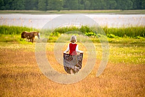 Latvian woman in traditional clothing in field.