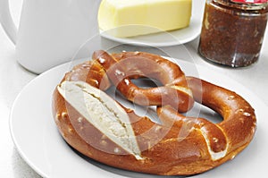 A laugenbrezel, a german pretzel, on a set table for breakfast