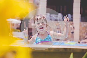 Laugh is the biggest indicator of a kidâ€™s happiness. Happy little girl playing in water outdoors in the swimming pool