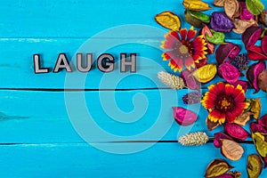 Laugh word on blue wood with flower