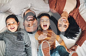 Laughing, above and portrait of a family on a bed for relaxation, bonding and quality time. Playful, smile and carefree