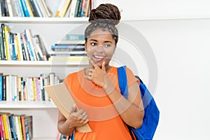 Laughing african american college student with backpack and paperwork