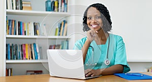 Laughing african american female doctor answering questions of patient online