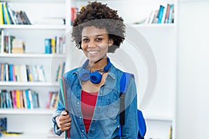 Laughing african american female student with backpack and paperwork