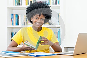 Laughing african american female student with book