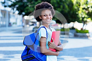 Laughing african american female student in city walking to university