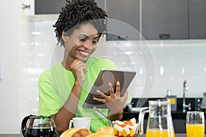 Laughing african american female student learning online with tablet computer