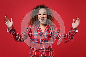 Laughing african american girl in pajamas homewear resting at home isolated on red wall background. Relax good mood