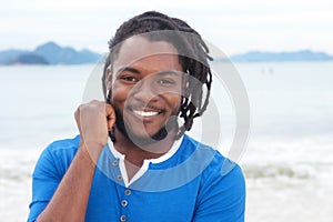 Laughing african american guy with dreadlocks at beach
