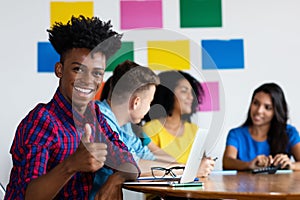 Laughing african american male student at computer with group of students