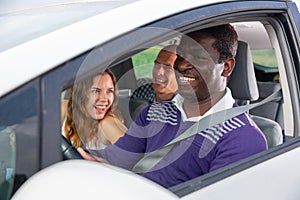 Laughing african american man driving car with cheerful passengers