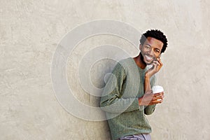 Laughing african man holding coffee talking on smart phone