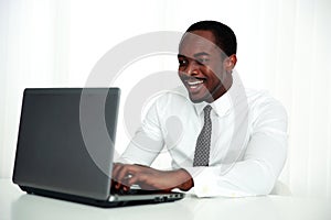 Laughing african man using laptop