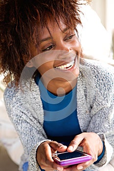 Laughing african woman holding mobile phone