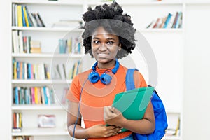 Laughing afro american female college student with backpack and paperwork