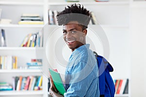 Laughing afro american male student with backpack and paperwork