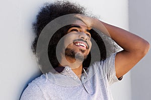 Laughing afro man with hand in hair looking away