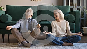 Laughing aged spouses sitting on floor in lotus position