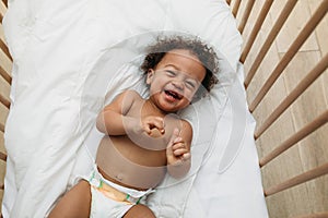 Laughing baby boy lying in a crib