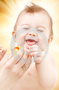 Laughing baby boy in mother hands with rubber duck