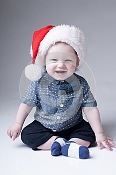Laughing baby boy in santa hat.