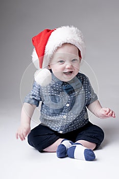 Laughing baby boy in santa hat.