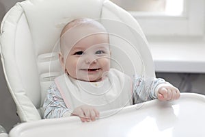 Laughing baby eating in highchair