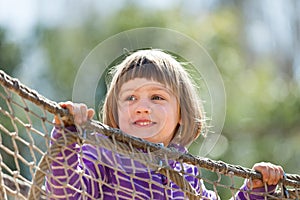 Laughing baby girl climbing on ropes