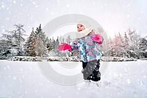 Laughing baby girl runs in the snow