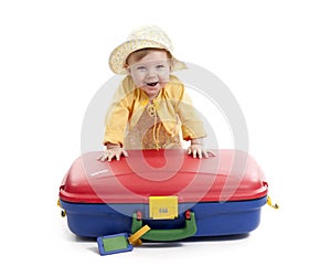 Laughing baby with red and blue suitcase, on white