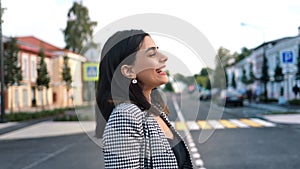 Laughing beautiful fashion young woman walking European city street with positive emotion closeup